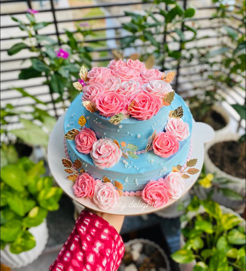 Beautiful blue cake with pink roses and gold leaves